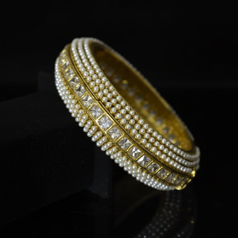 Gold bracelet with diamond accents on a dark background, featuring the brand 'Saheli'.
