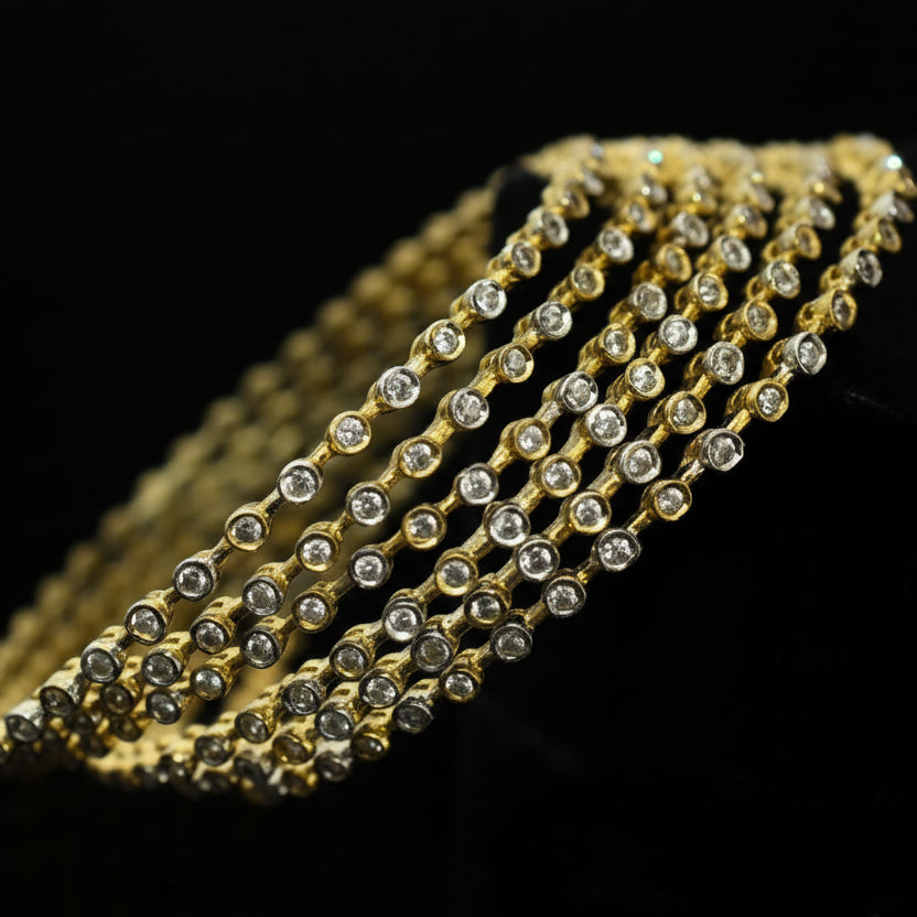 Gold bracelet with clear stones on a dark background, featuring the brand 'Saheli'.