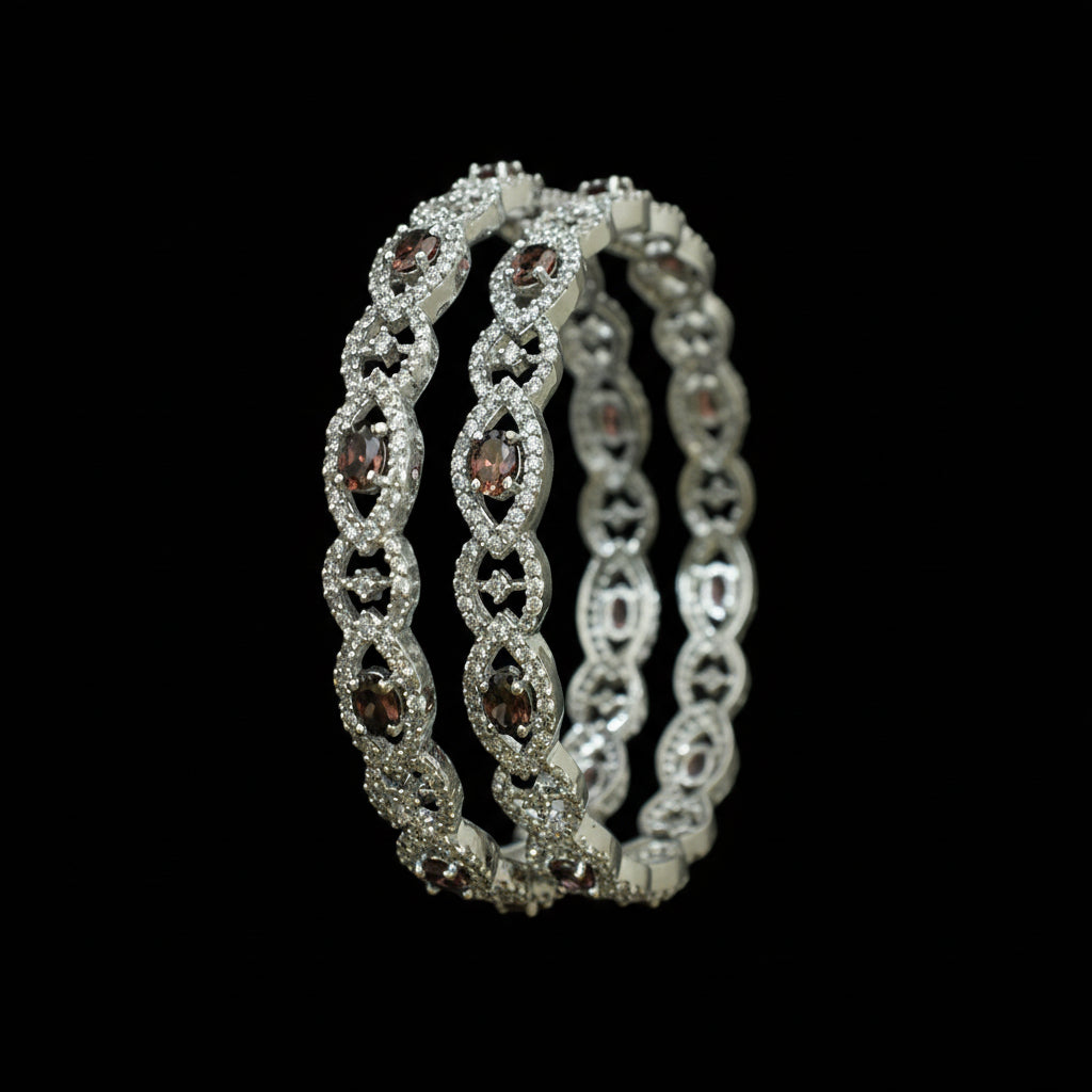 Silver bangles with gemstones on a black background, featuring the brand 'Saheli'.