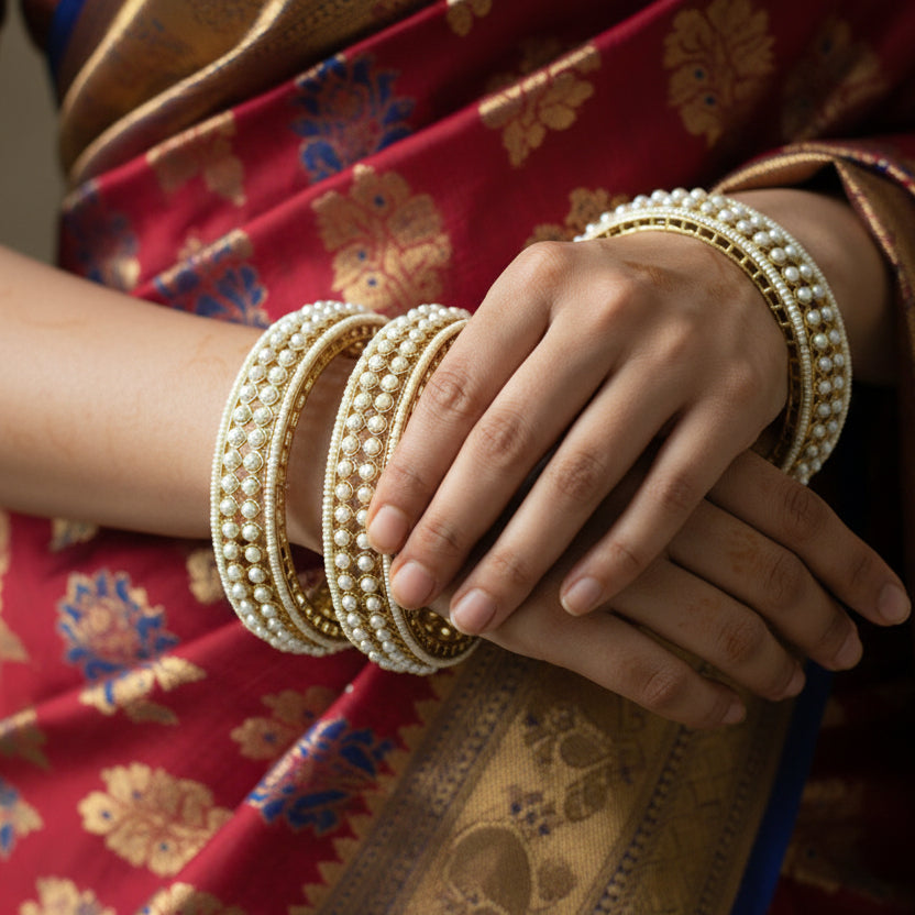 Gold and pearl bangles on a dark background with 'Saheli' branding.