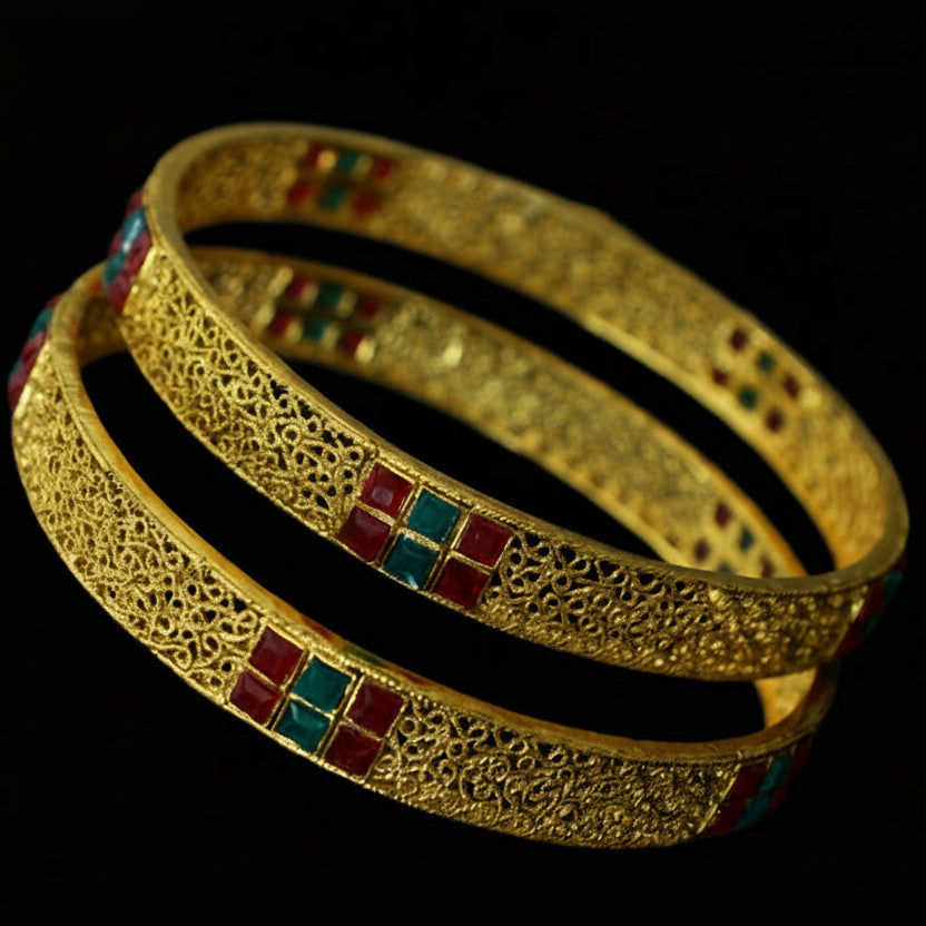 Gold bangles with colorful stones on a dark stand against a gray background, branded 'Saheli'.