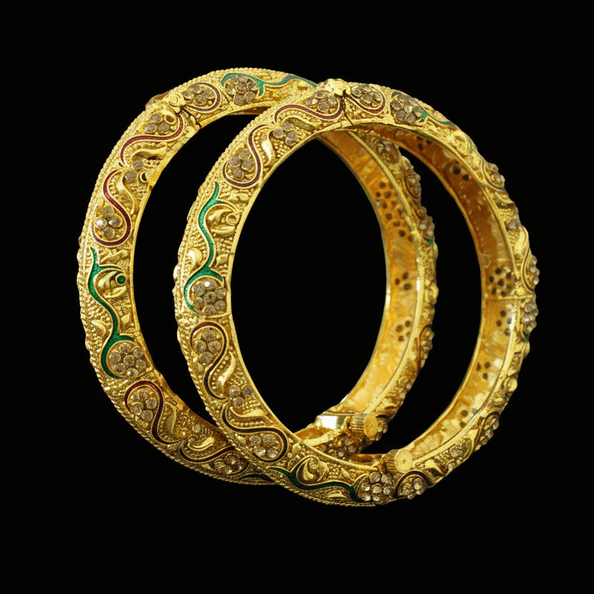 Pair of gold bangles with intricate designs on a gray background, featuring the brand 'SAHELI'.