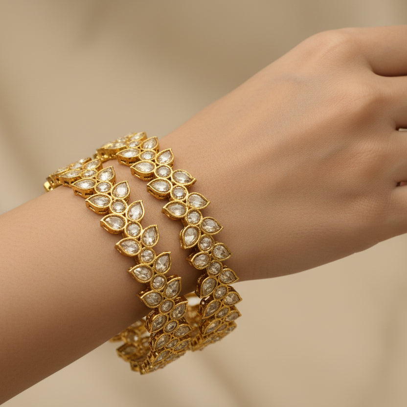 Gold bracelet with diamond-like stones on a black background, featuring the brand 'Saheli'.
