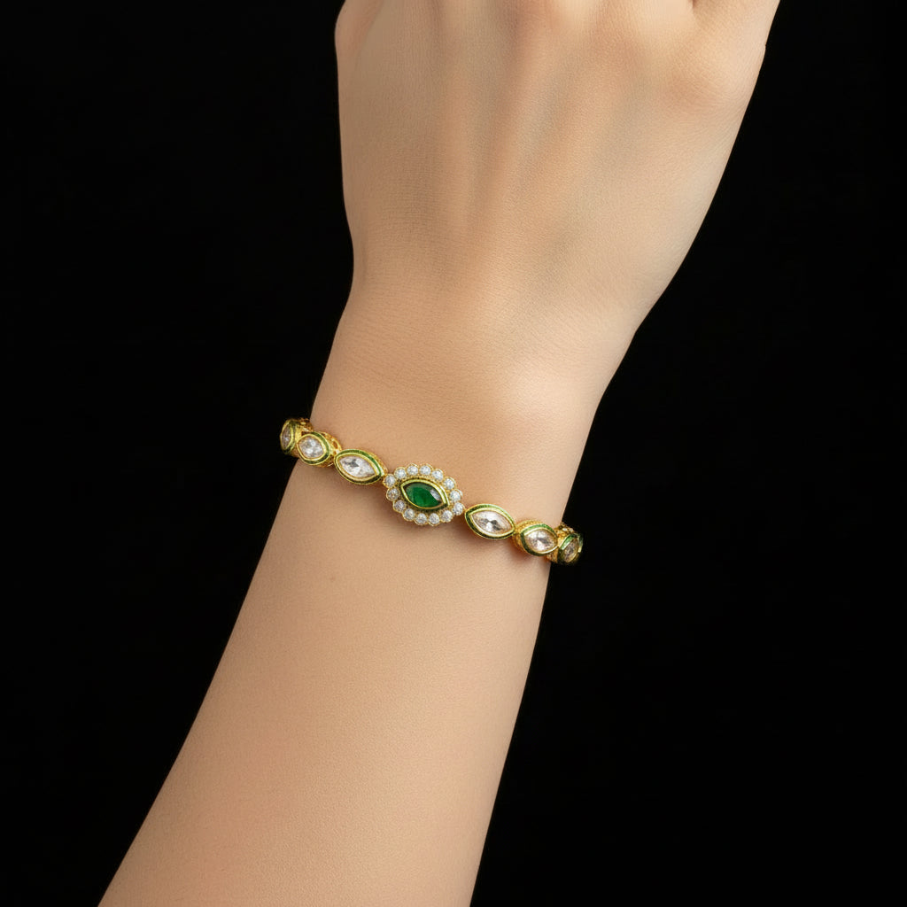 Gold bracelet with green gemstones on a gray background, featuring the brand 'Saheli'.