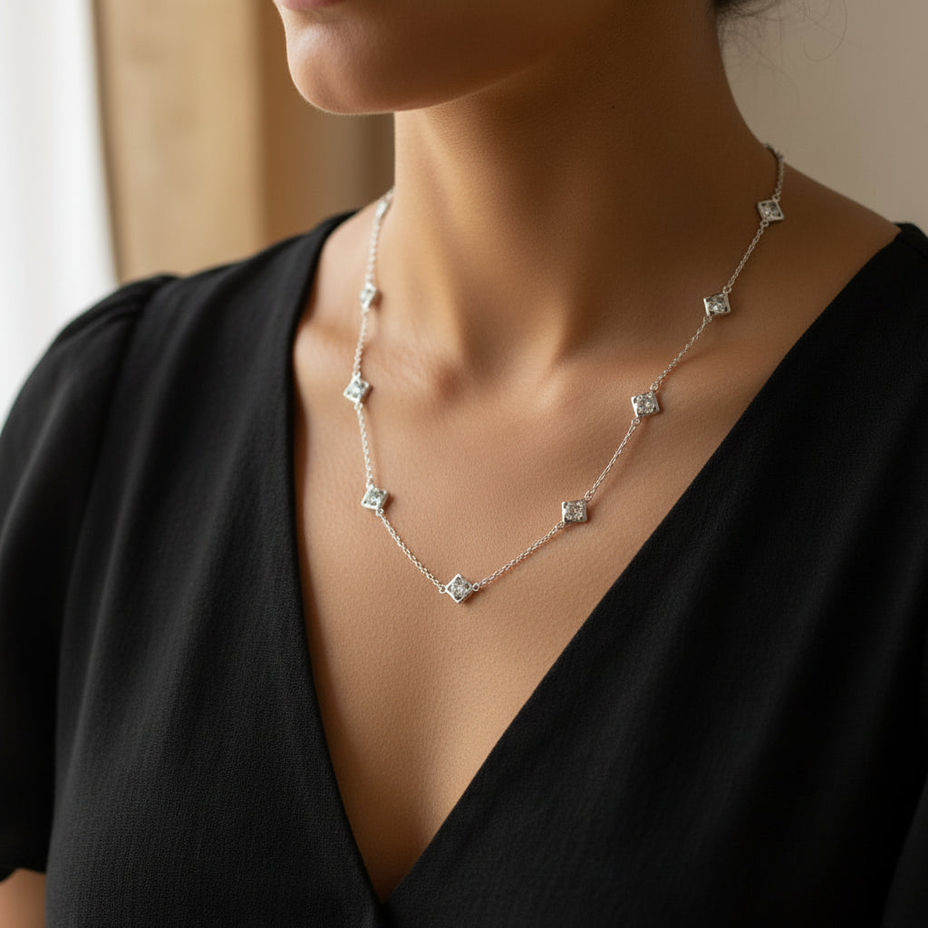 Silver necklace with diamond-like beads on a black background, featuring the brand 'SAHELI'.