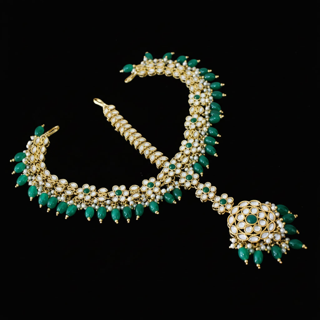 Gold and green necklace with pendant on a dark background, featuring the brand 'Saheli'.