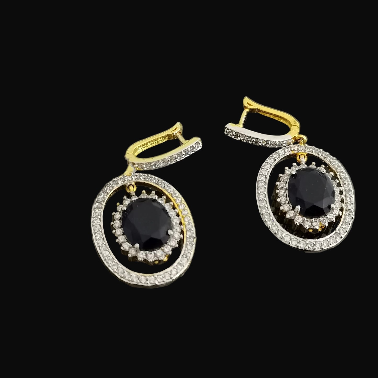 Gold and black earrings with SAHELLI branding on a dark background