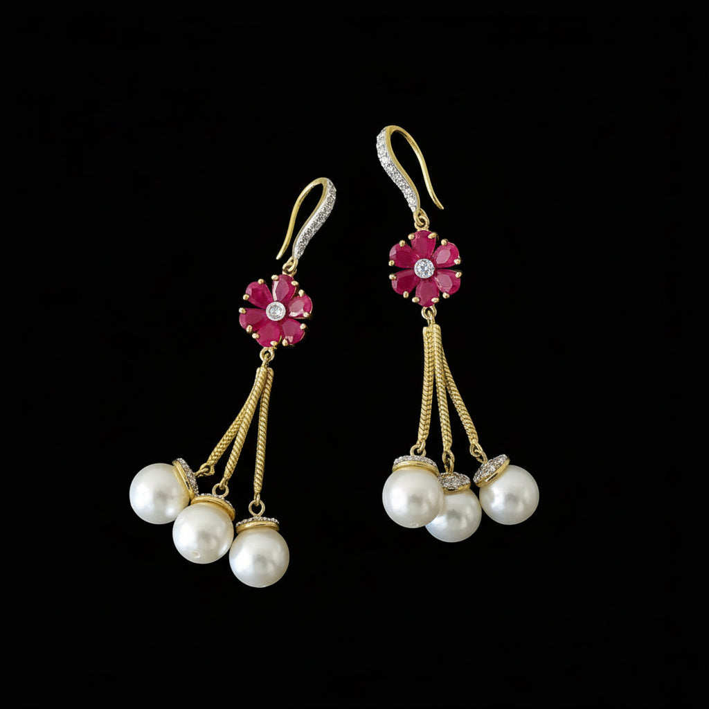 Pair of earrings with pearls and red gemstones on a dark background, branded 'Saheli'.