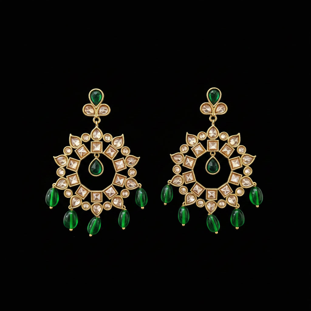 A pair of gold-toned Kundan chandelier earrings with green teardrop beads and clear stones, displayed on a gray Y-shaped stand against a gray background. The brand logo 'SAHELLI MY BEST FRIEND' is visible at the top.