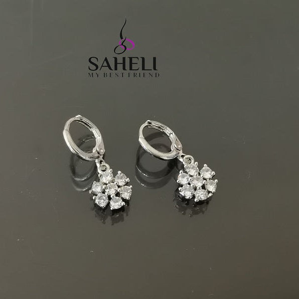 Pair of silver earrings with gemstones on a dark background, featuring the brand 'Saheli'.