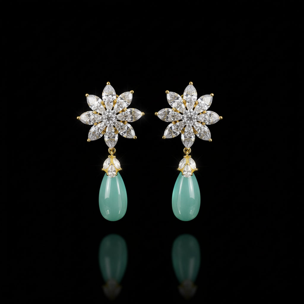 Pair of earrings with star-shaped top and teardrop-shaped bottom on a dark background