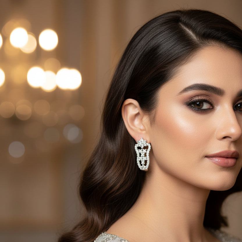 Silver earrings on a black stand with 'Saheli' branding on a dark background