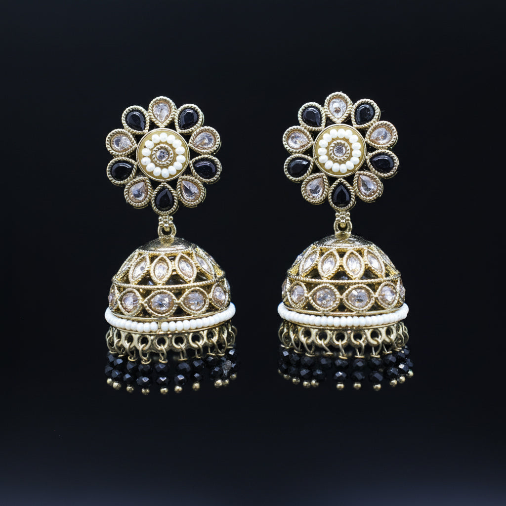 Pair of gold and black floral earrings on a dark background