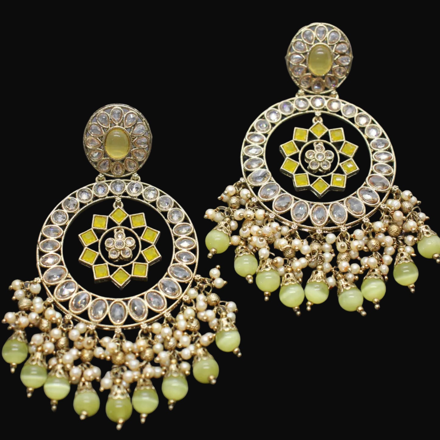 Ornate earrings with green beads on a dark background