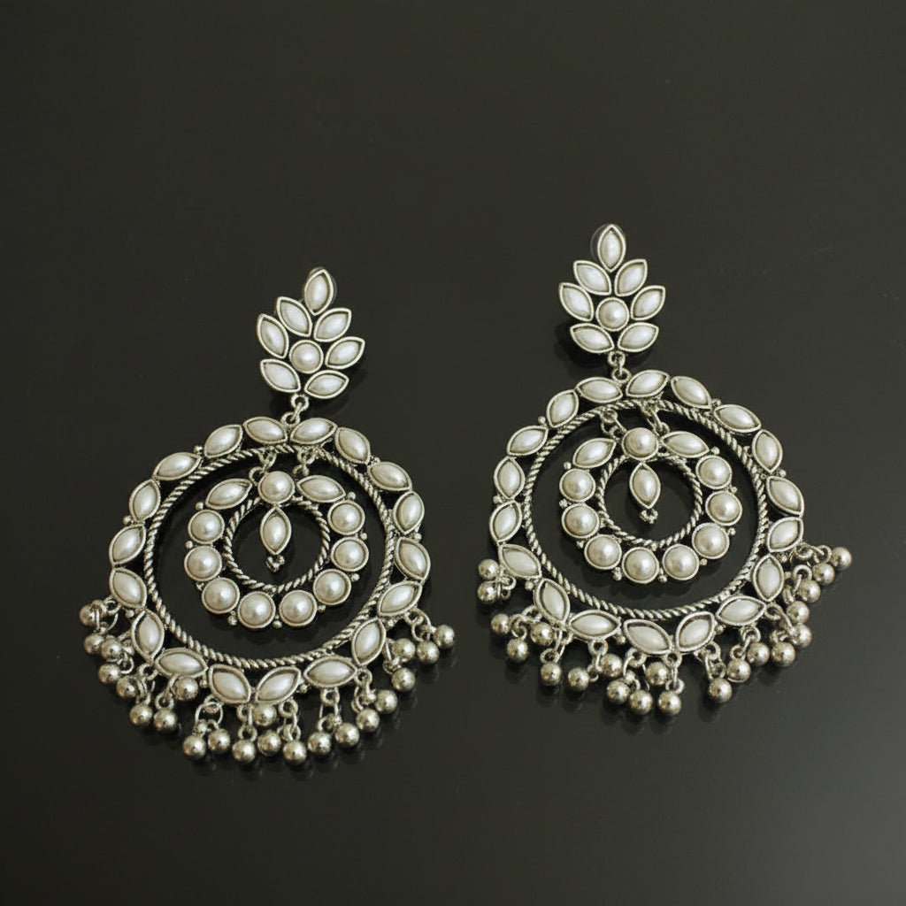 Pair of silver earrings with intricate designs on a black background