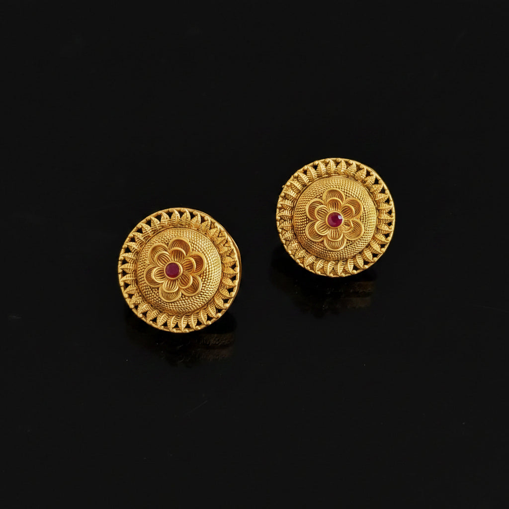Pair of gold earrings with floral design and red gemstones on a black background