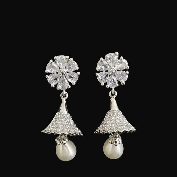 Pair of silver earrings with floral top and pearl drop on a black background