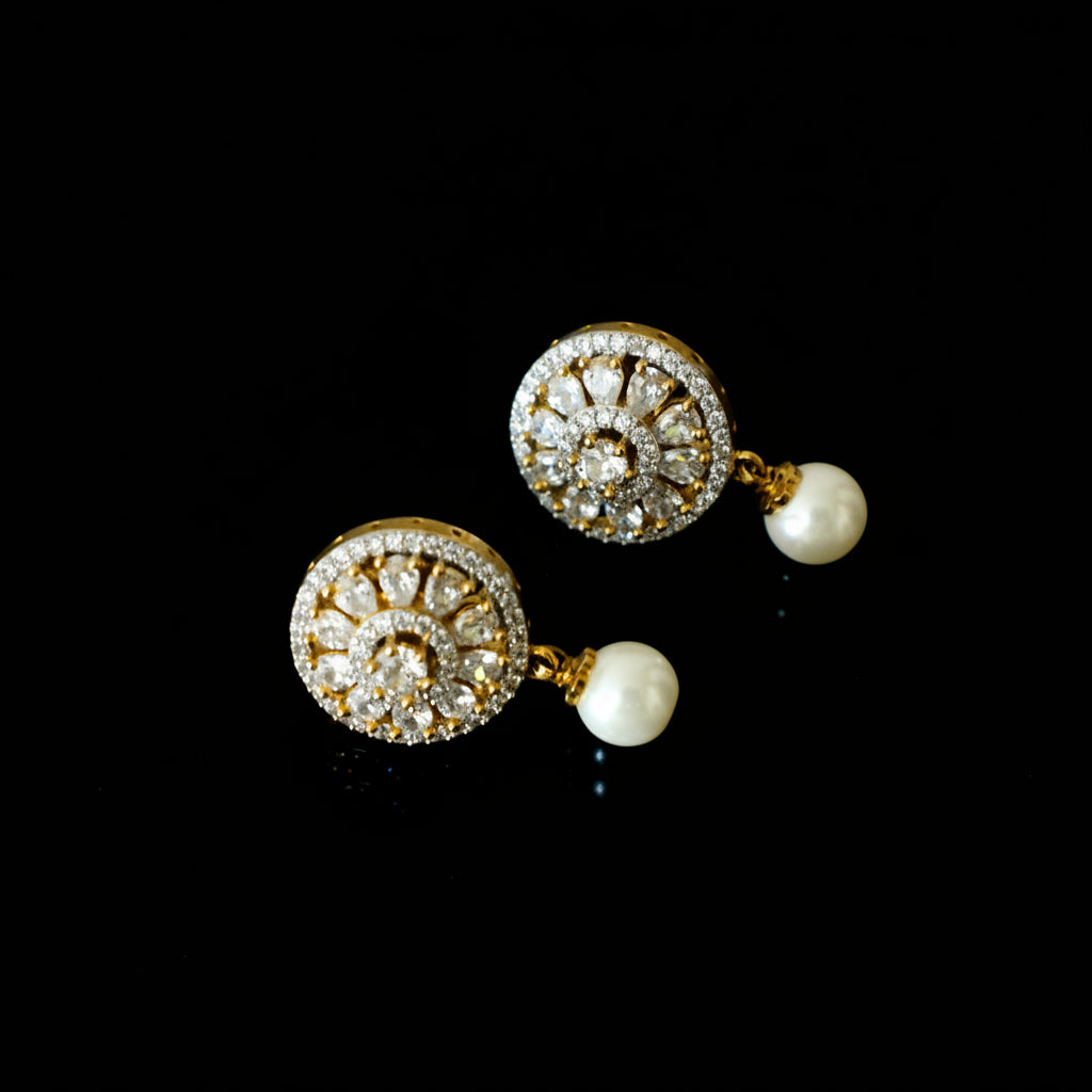 Gold and pearl earrings on a dark background with 'SAHELI' branding.