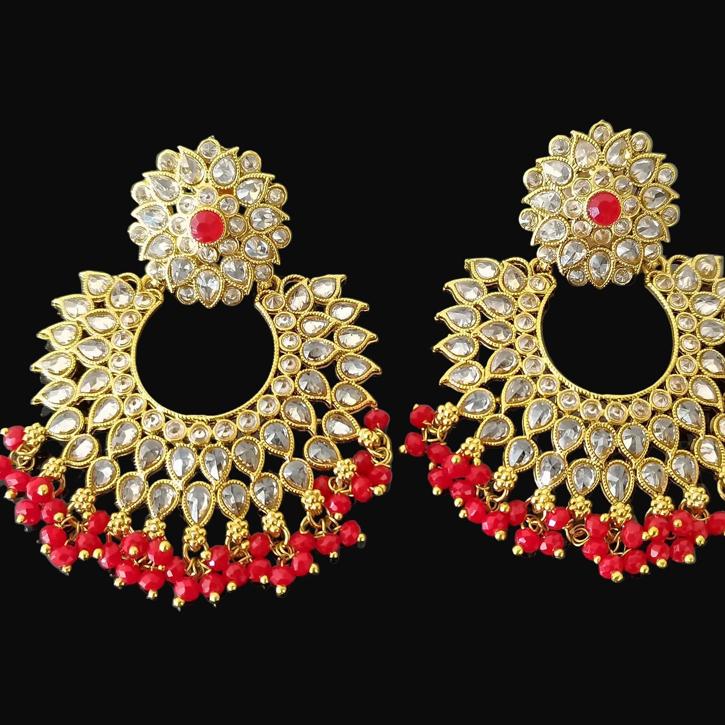 Gold and red earrings with 'Saheli' branding on a dark background