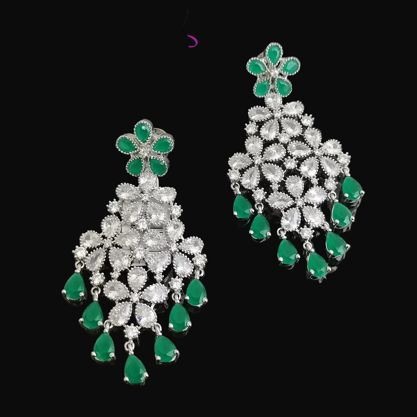 Pair of silver earrings with green gemstones on a dark background, branded 'Saheli'.
