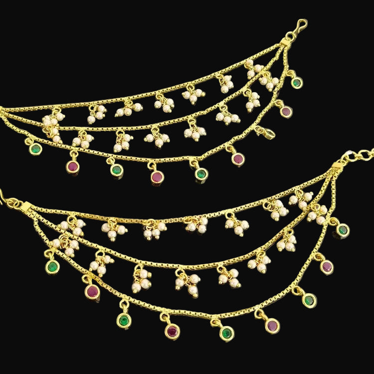 Gold necklace with pearl and gemstone pendants on a dark background, featuring the brand 'Saheli'.