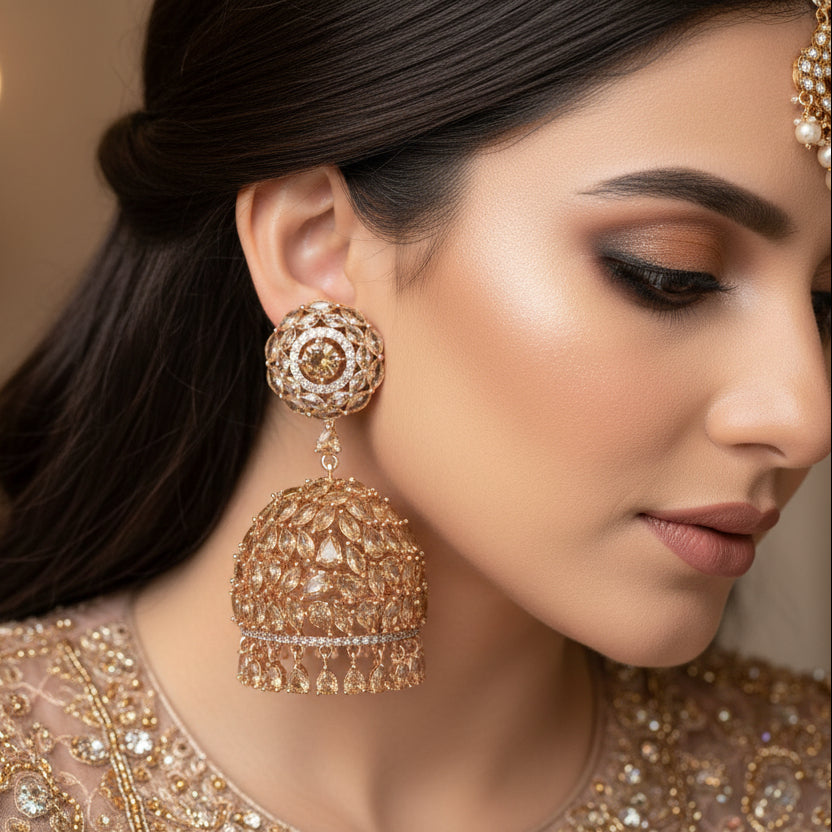 Pair of gold earrings with intricate designs on a black stand.