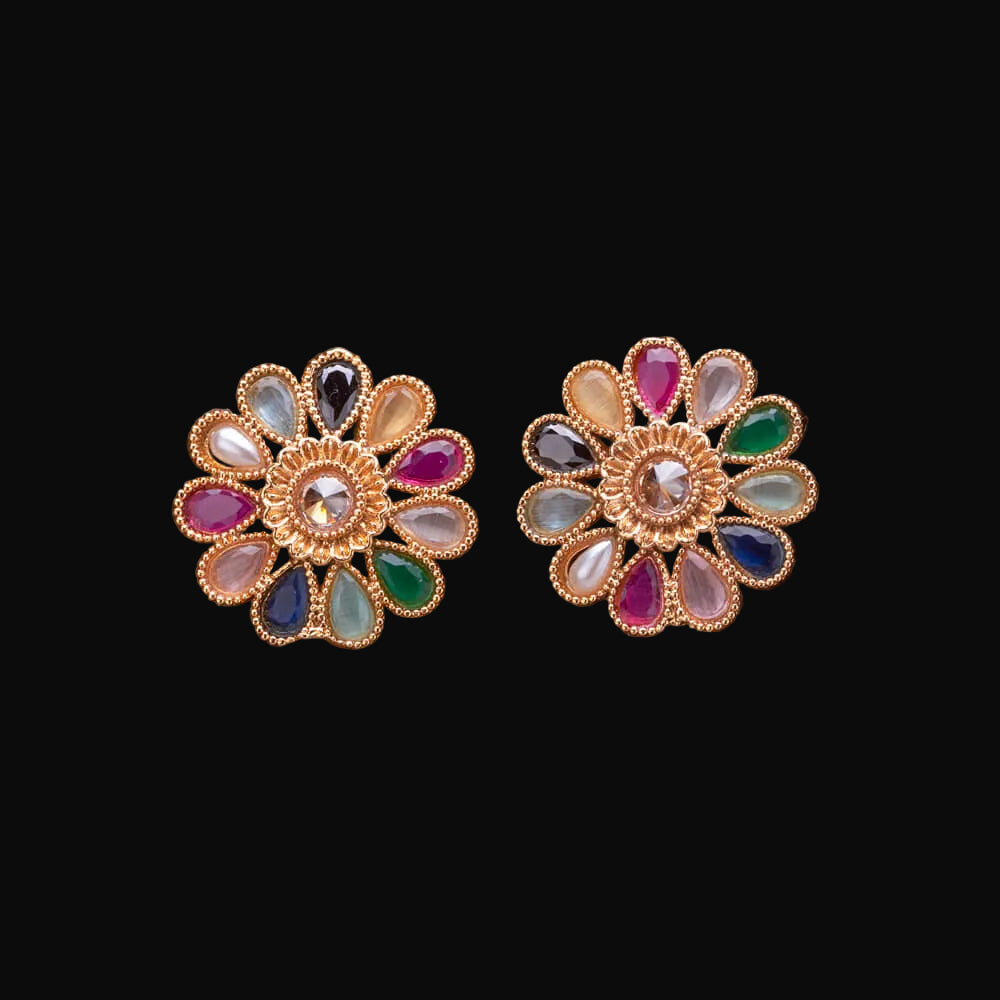 Pair of floral earrings with colorful gemstones on a wooden surface