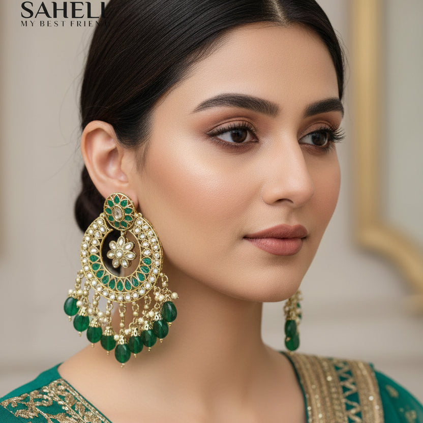 Ornate green and gold earrings with 'SAHELI' branding on a dark background