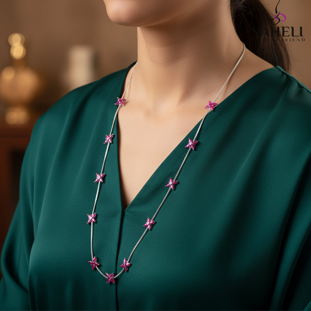 Necklace with pink flower pendants on a gray background, featuring the brand 'Saheli'.