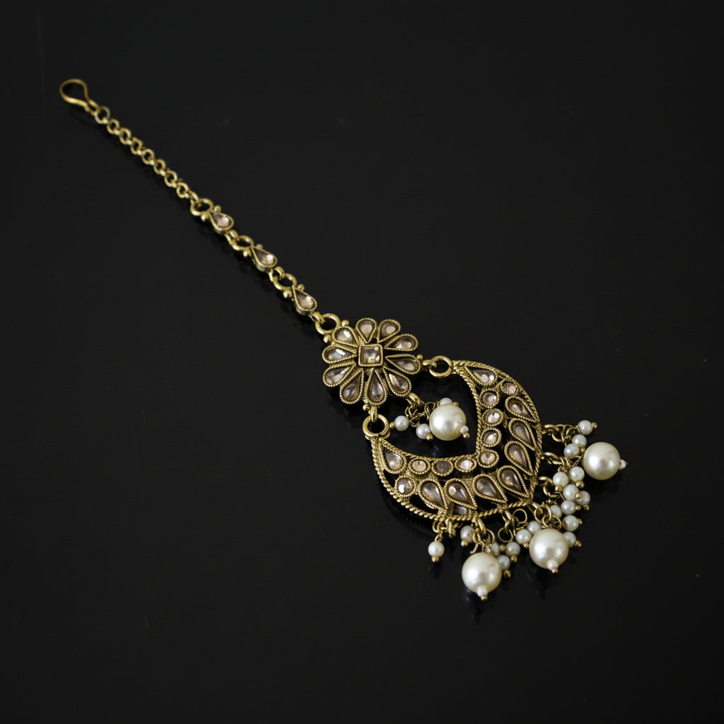 Decorative hair accessory with gold chain and pearl-like beads on a dark background