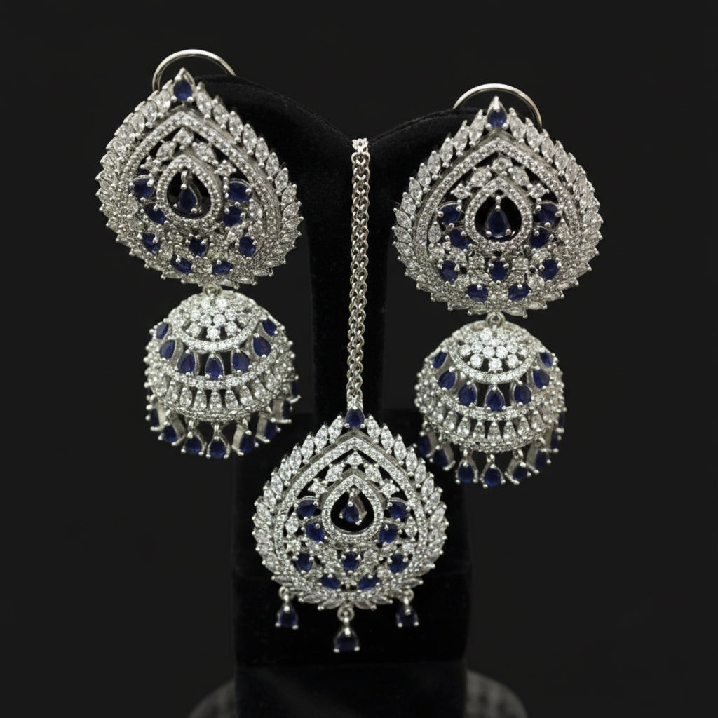 Ornate silver earrings with blue gemstones on a dark background