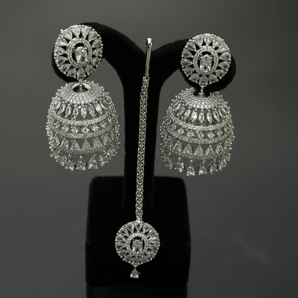 Silver earrings on a black stand with 'Saheli' branding.