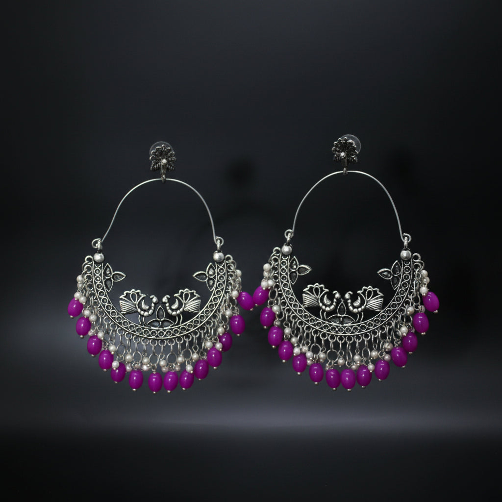 Silver hoop earrings with pink beads on a dark background