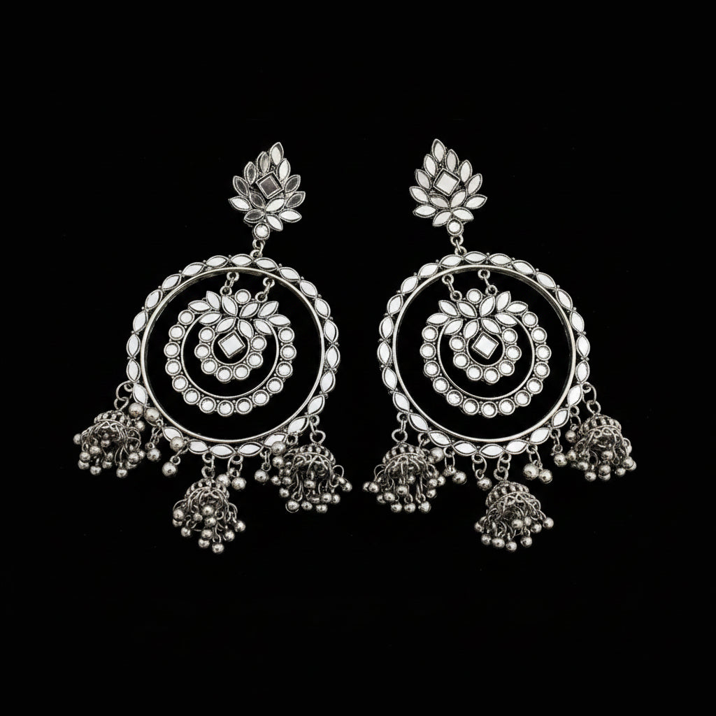 Pair of silver earrings with intricate designs on a dark background