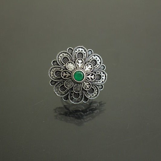 Silver ring with a green gemstone on a dark gray background