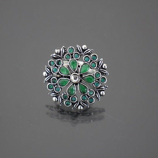 Silver ring with green gemstones on a gray background