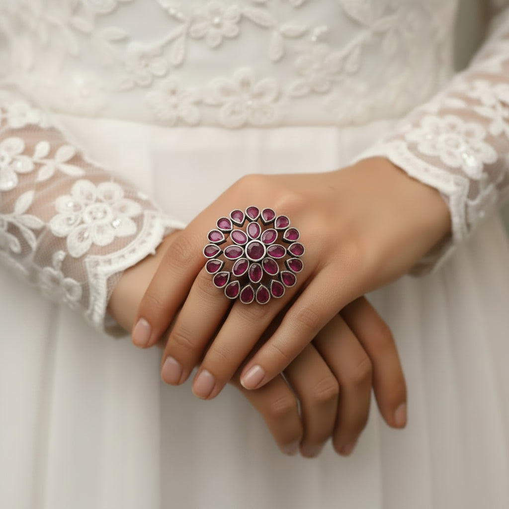 Ring with pink gemstones on a black mannequin hand against a gray background