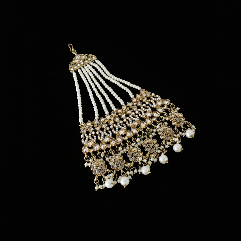 Ornate necklace with white beads and gold accents on a dark background, featuring the brand 'Saheli'.