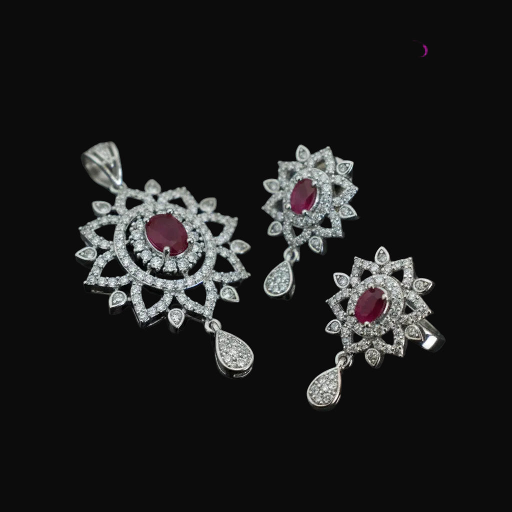 Jewelry set with red gemstones and silver accents on a dark background, featuring the brand 'Saheli'.
