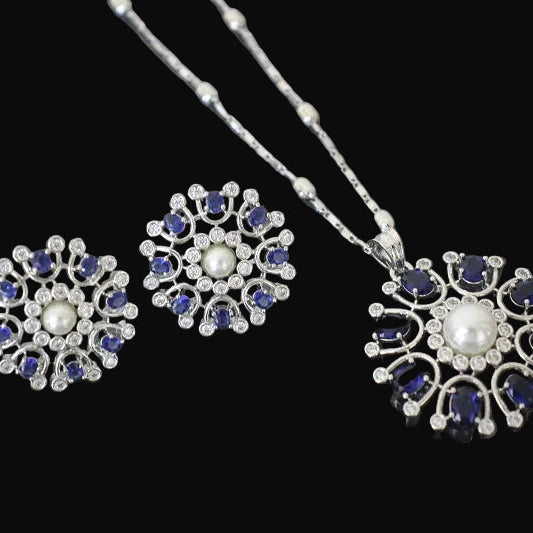 Jewelry set with floral designs featuring pearls and blue stones on a dark background
