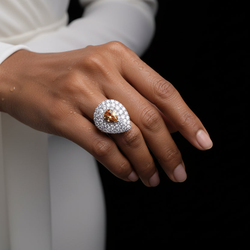 Teardrop-shaped gemstone held between fingers with a blurred background