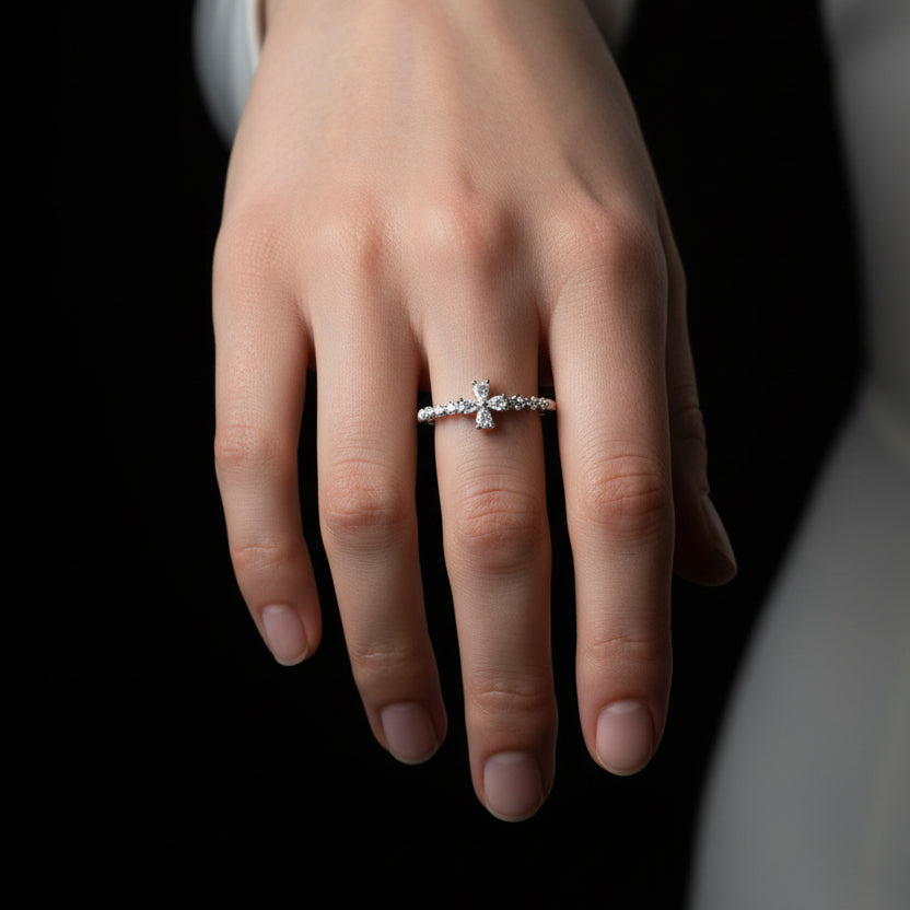 Silver cross ring on a black mannequin hand against a dark background