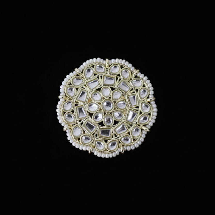 Decorative ring with gemstones on a black glove against a dark background