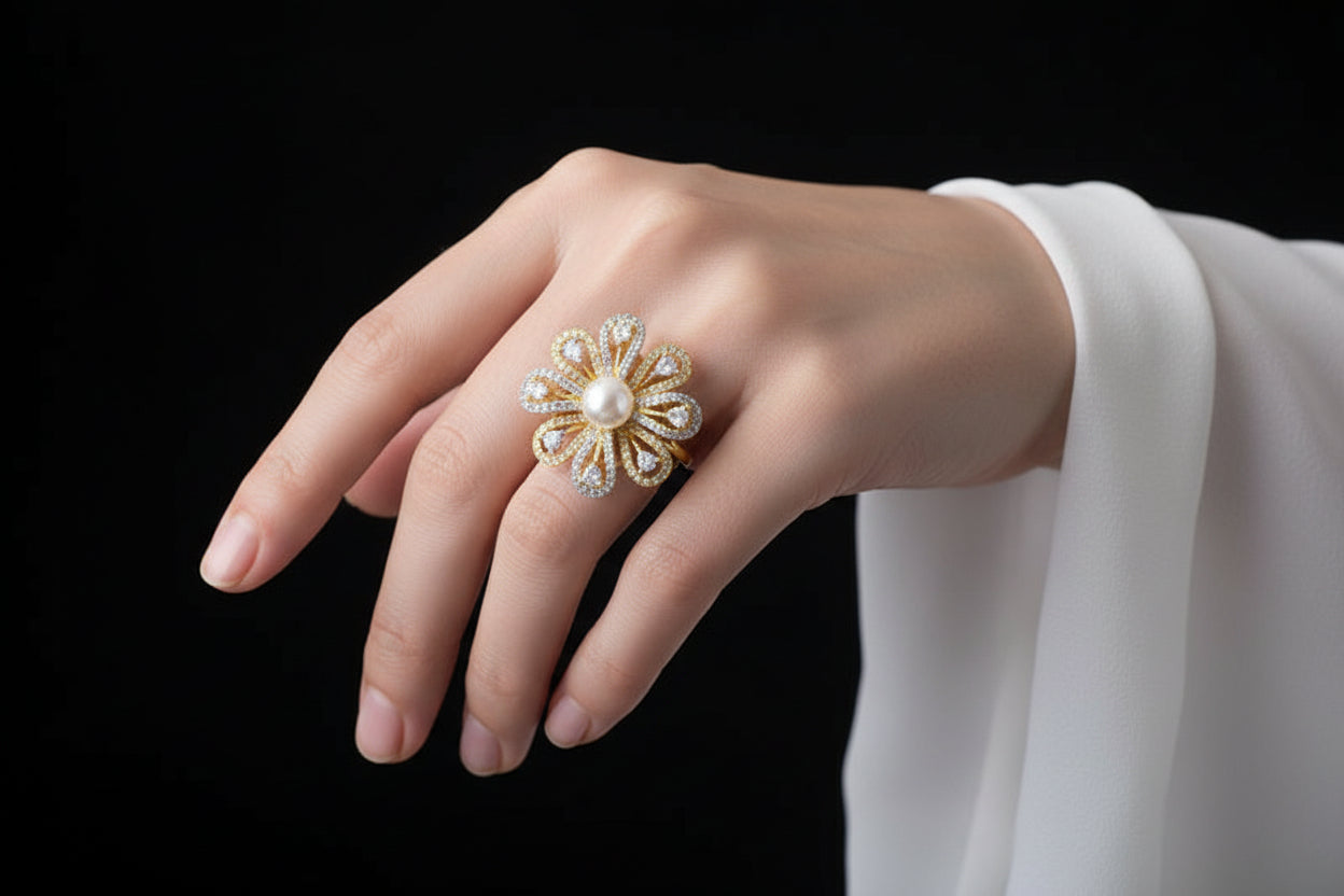 Gold flower-shaped ring with a pearl center on a black mannequin hand.