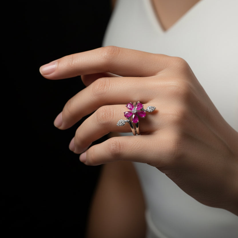 Silver ring with pink gemstones on a gray background, featuring the brand 'Saheli'.