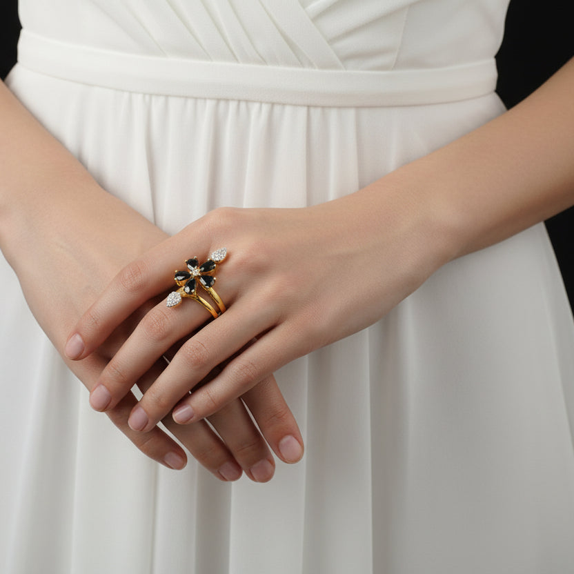 Gold and silver floral ring on a black mannequin hand with 'SAHELI' branding.