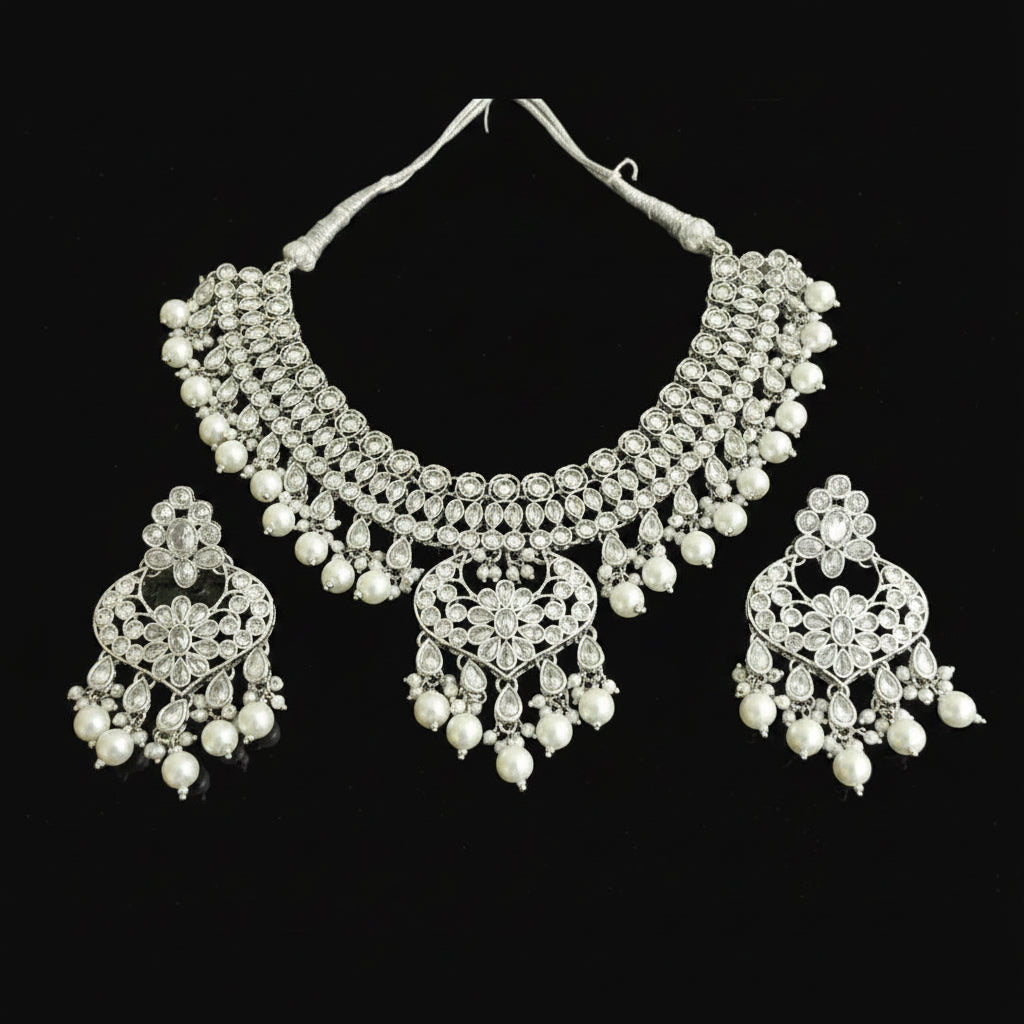 Silver necklace and earrings set on a reflective surface