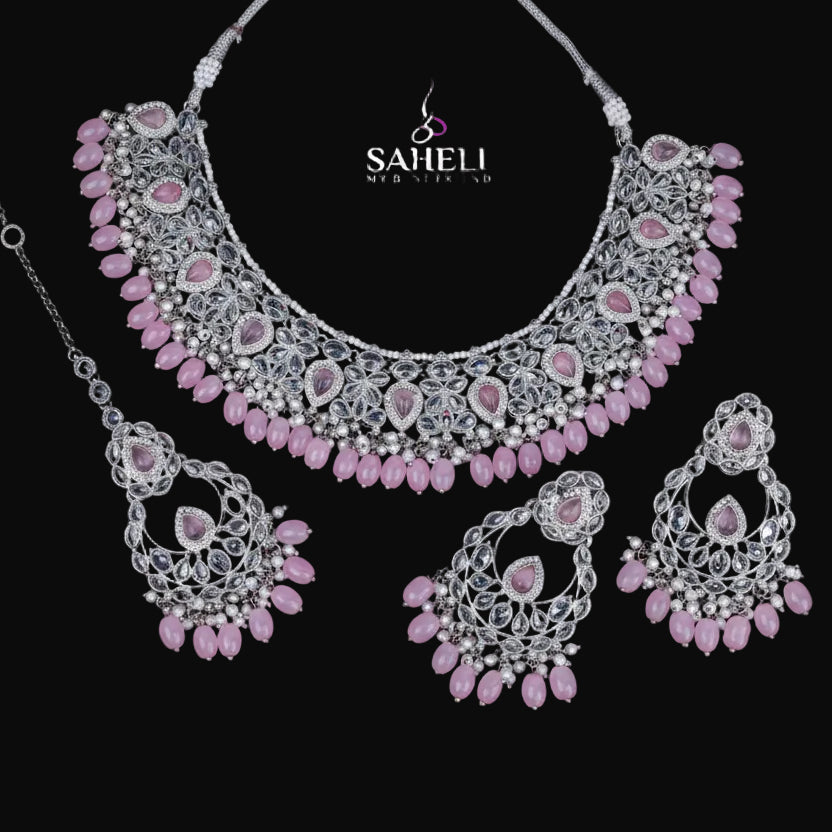 Jewelry set with pink stones and silver accents on a black background, featuring the brand 'Saheli'.