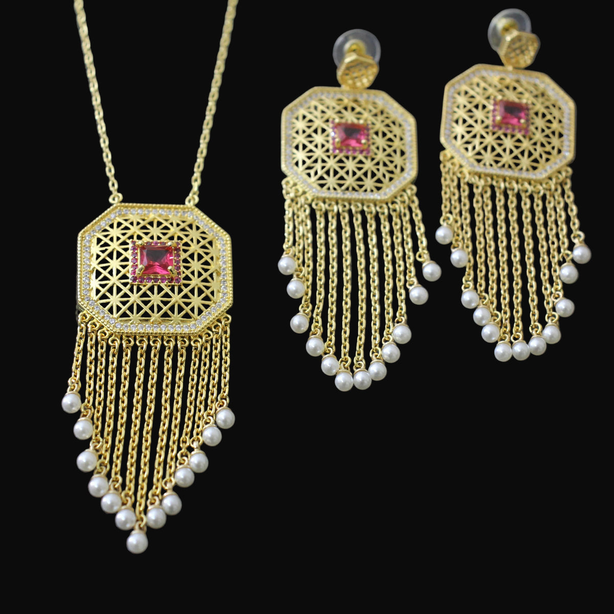 Gold necklace and earrings with red gemstones on a dark background
