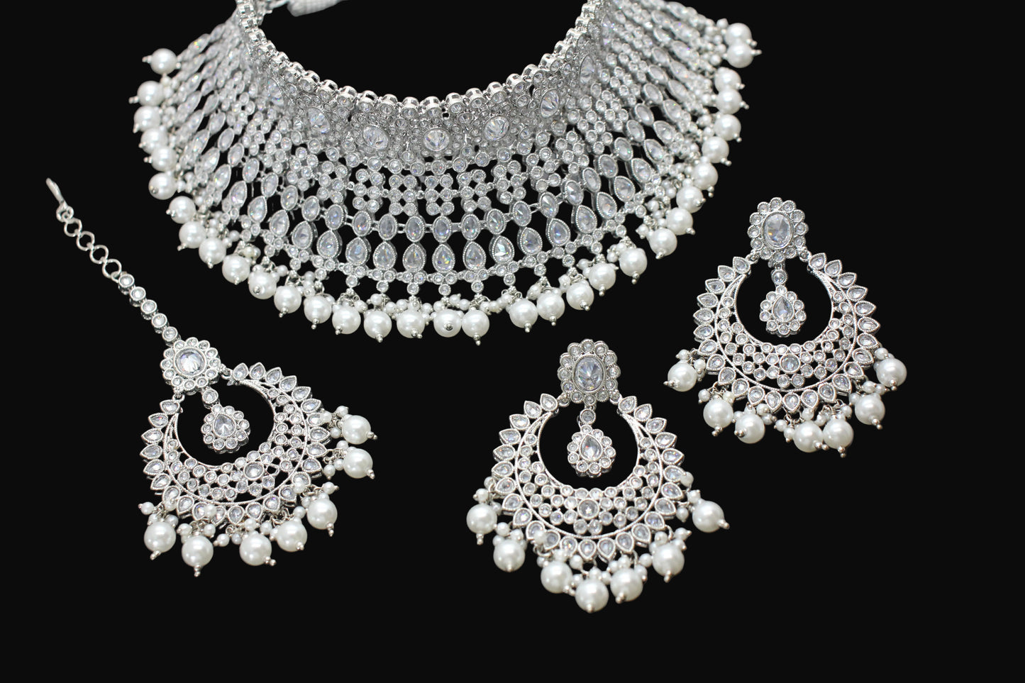 Silver necklace and earrings set on a dark background